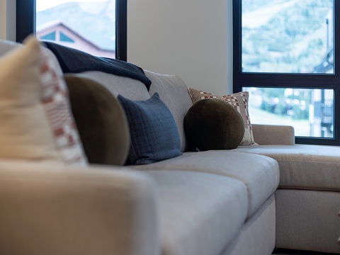 Sink into the plush sectional sofa and take in the natural light streaming through the floor-to-ceiling windows. Mix-and-match pillows invite you to curl up and relax in your stylish mountain retreat.
