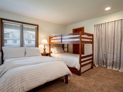 Rest easy in your serene bedroom, where a queen bed and sturdy bunk bed provide flexible sleeping arrangements. Soft natural light filters through wooden blinds, while plush carpeting and cozy linens create a welcoming retreat for the whole family.