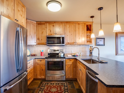 Gather around a full kitchen featuring warm wood cabinetry, stainless appliances, and everything you need to whip up your favorite meals together during your mountain getaway.
