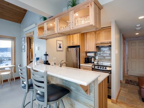 Your bright, airy kitchen features warm wood cabinetry, stainless appliances, and a welcoming breakfast bar—perfect for morning coffee or preparing meals with loved ones by your side.