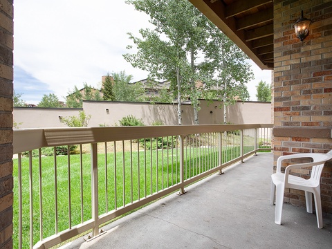Step onto your private covered balcony, where morning coffee feels extra special. Lush green lawn stretches below, framed by mature trees and peaceful neighborhood views for your relaxation.