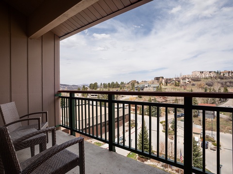 Private balcony with comfortable seating overlooks a scenic mountain and residential landscape, offering a peaceful retreat to enjoy fresh air and tranquil views.
