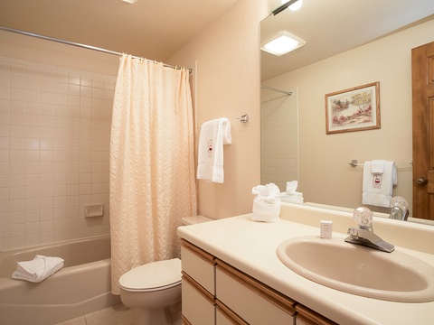 Step into your private bathroom with fresh towels, a spacious tub-shower combo, and thoughtful touches ready for your comfort and relaxation.