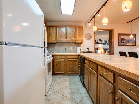 Your fully equipped kitchen with oak cabinetry and spacious countertops is perfect for preparing home-cooked meals. Natural skylights bathe the space in warmth, while pendant lighting creates a cozy ambiance for evening gatherings.