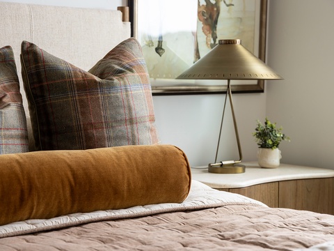 Sink into soft linens and rest your head on plush pillows in this inviting bedroom, where warm textures and elegant touches promise you a peaceful night's sleep.