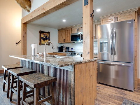 Your fully equipped kitchen features natural wood cabinetry, stainless steel appliances, and granite countertops. Gather at the rustic breakfast bar with seating for casual meals and morning coffee.