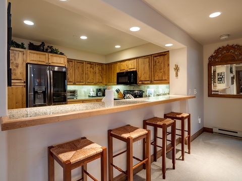 Gather at the breakfast bar with friends and family. Warm wood cabinetry, granite countertops, and modern appliances create a welcoming space for preparing meals and making memories together.