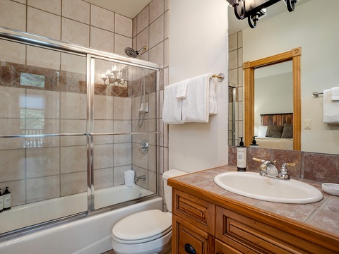 Step into your serene private bathroom, featuring a spacious tiled shower, plush white towels, and warm wood accents that create a relaxing retreat after a day of adventure.