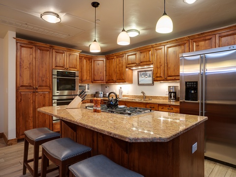 Your gourmet kitchen features rich wood cabinetry, gleaming granite countertops, stainless steel appliances, and a spacious island with seating—perfect for gathering and preparing memorable meals together.