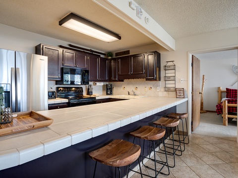 Gather your group around this spacious kitchen island, perfect for morning coffee or meal prep. Dark wood cabinets and modern appliances await your culinary adventures.