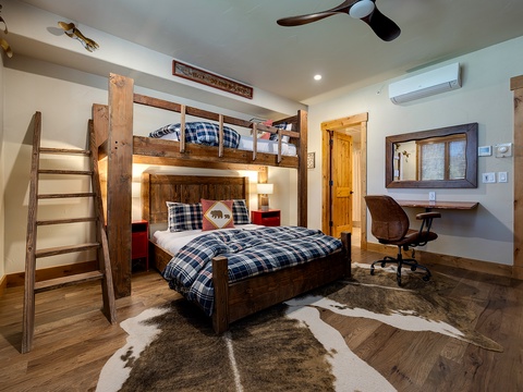 This rustic bunk room with custom wood beams and cozy plaid bedding offers the perfect mountain retreat for your family, complete with a desk area for remote work and climate control for year-round comfort.