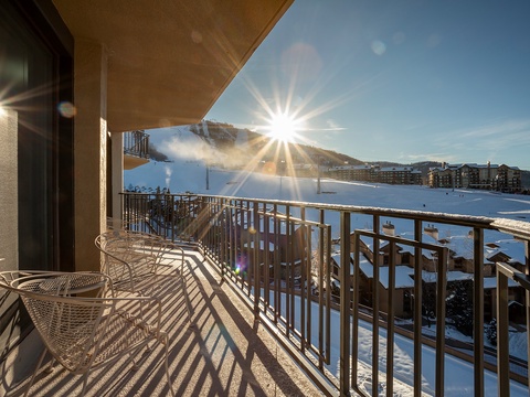 A private balcony overlooks snow-blanketed slopes and mountain terrain at a ski resort, offering winter scenery and mountain views during daylight hours.