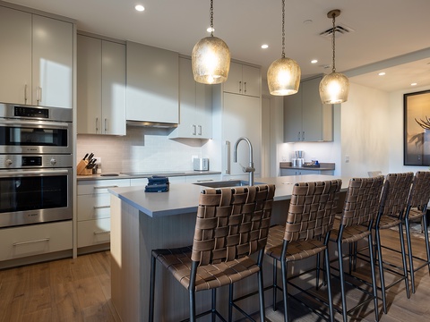Gleaming pendant lights illuminate this spacious gourmet kitchen, where modern appliances and warm wood tones create the perfect gathering space for your vacation.