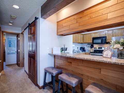 Your fully equipped kitchen features warm wood cabinetry, granite countertops, and modern appliances—perfect for brewing morning coffee or preparing a cozy meal after a day of adventure.