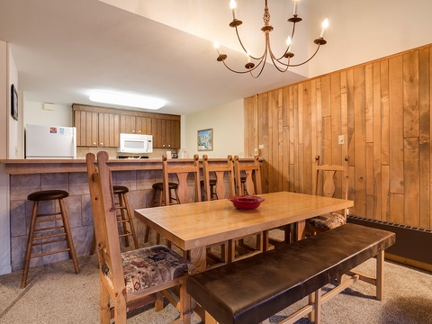 Gather around the spacious dining table with warm wood accents and a charming chandelier, perfect for memorable meals together. The breakfast bar offers extra seating for casual bites.