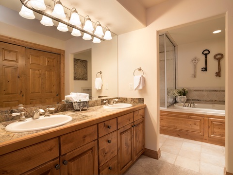 Step into your private spa-like bathroom with warm wood tones, dual vanities, and a soaking tub tucked into an elegant alcove.