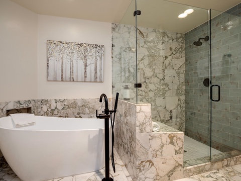Step into spa-like serenity with your private soaking tub, elegant marble finishes, and a spacious walk-in shower with rainfall head—your perfect retreat after a day of exploring.