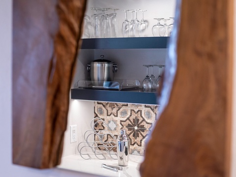 Your private bar nook awaits, featuring stylish glassware and a sleek ice bucket, set against charming patterned tile—perfect for crafting evening cocktails in style.