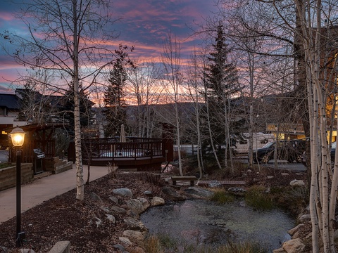 A residential neighborhood nestled among aspen and evergreen trees, framed by a stunning twilight sky painted in shades of pink and blue.