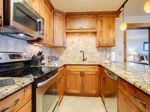 Cook your favorite meals in this fully equipped kitchen featuring granite counters, stainless appliances, and warm wood cabinetry with ample prep space for your group.