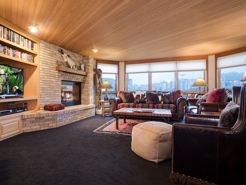 Unwind in your spacious living room with crackling fireplace, plush leather seating, and panoramic mountain views framing the space—your perfect retreat after a day exploring.