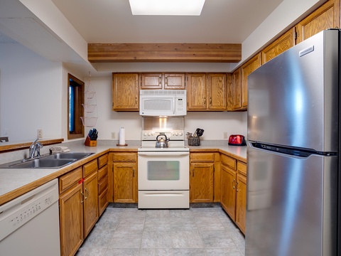 Cook up your favorite meals in this fully equipped kitchen with modern appliances, ample counter space, and natural light streaming through the skylight overhead.