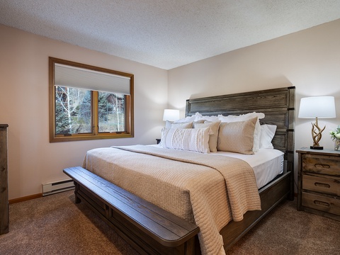 Settle into your cozy bedroom with a plush king bed, rustic wood furnishings, and peaceful winter views just outside your window—your perfect retreat after a day of adventure.