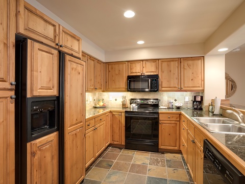 Your fully equipped kitchen features warm wood cabinetry, granite countertops, and modern black appliances—everything you need to whip up meals during your stay.