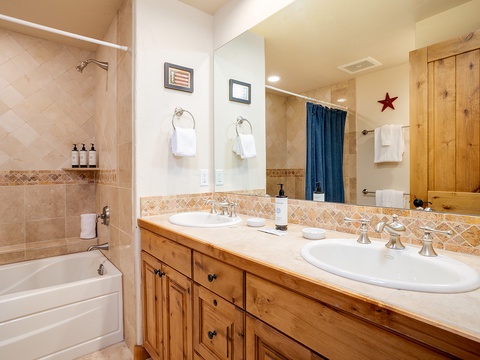 Your private bathroom features double sinks with rustic wood cabinetry, a tiled tub-shower combo, and thoughtful touches like fresh towels and quality toiletries to help you unwind after a day of adventure.