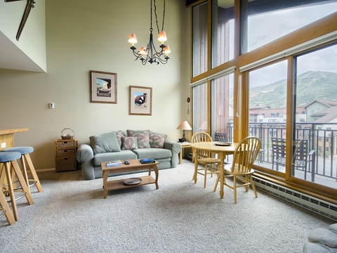 Settle into your bright, spacious living area with soaring ceilings and expansive mountain views. Relax on the cozy sofa, enjoy meals at the dining table, and take in the stunning scenery right from your windows.