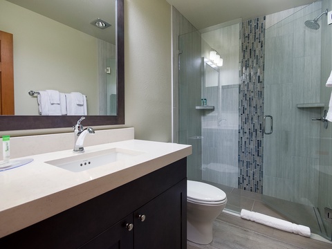 Step into your spa-like bathroom featuring soft tile, a modern vanity, and a walk-in shower with elegant mosaic accents—everything you need for a refreshing start to your day.