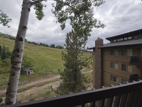 Mountain property nestled on a hillside with surrounding natural landscape and seasonal greenery under open skies.