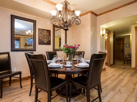 Gather around this elegant dining table, perfectly set for memorable meals together. The warm chandelier and fresh flowers create an inviting atmosphere for your group to share stories and laughter.