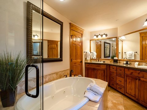 Unwind in your luxurious spa-like bathroom with a jetted soaking tub, elegant dual vanities, and plush towels ready for ultimate relaxation after a day of adventure.
