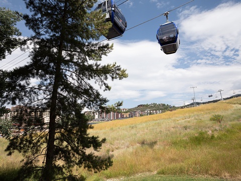 A gondola system provides convenient transportation near the property, set in a scenic hillside area with open meadows and nearby residential buildings.