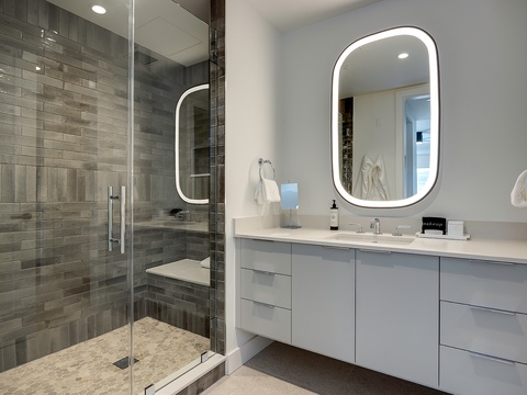 Refresh in your modern bathroom with a spacious walk-in shower, elegant LED-lit mirror, and sleek double vanity designed for your comfort.