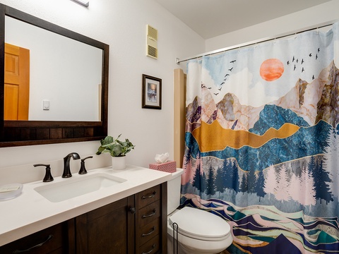 Your bright, modern bathroom features a striking mountain-sunset shower curtain that brings nature indoors, fresh linens, and a spacious vanity to start your day refreshed.