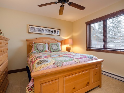 Drift off under a ceiling fan in this inviting bedroom, where a handcrafted quilt and warm wood furniture create a cozy mountain retreat you'll love returning to.