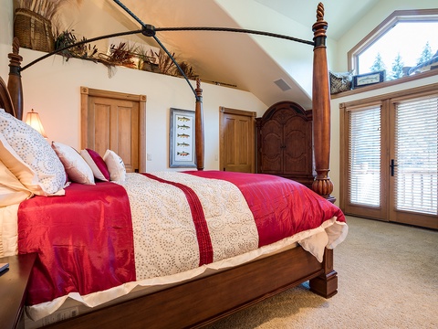 Sink into this elegant four-poster bed dressed in luxurious linens. Large windows frame peaceful forest views, while rustic touches create your perfect mountain retreat.