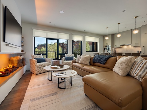 Sink into plush seating by the fireplace and unwind in your bright, open living space. Floor-to-ceiling windows frame neighborhood views while the fully equipped kitchen invites you to gather and feel right at home.
