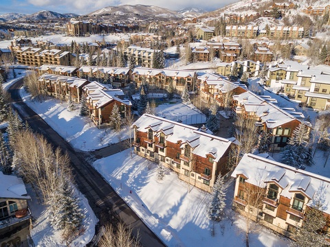 A picturesque mountain resort community blanketed in fresh snow, surrounded by snow-capped peaks and evergreen forests, offering a scenic alpine setting for winter getaways.