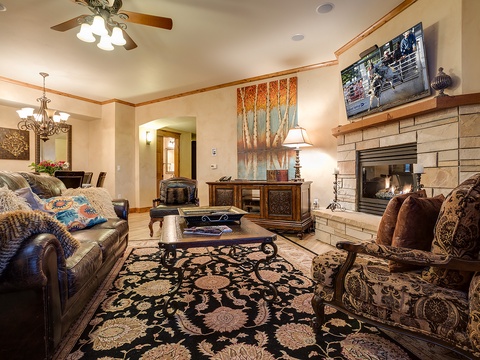 Unwind in your spacious living room featuring plush seating, a warming stone fireplace, and elegant décor. Curl up with your favorite show on the flat-screen TV or simply savor the cozy, inviting ambiance.