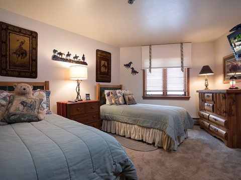 Relax in this charming Western-themed bedroom with two comfortable beds, rustic wood furnishings, and soft lighting that creates a cozy retreat after your adventures.