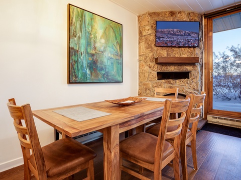Gather around this inviting dining table with seating for four, where rich wood tones and mountain views through the window create a warm atmosphere for your memorable meals together.
