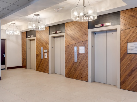 The elevator lobby welcomes you with contemporary design featuring diagonal wood paneling and elegant lighting for easy floor access.