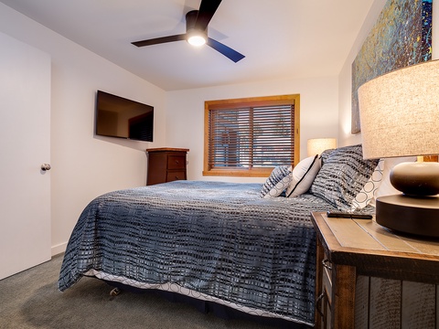 Unwind in your peaceful bedroom with a plush bed, soft lighting, and modern comforts like a ceiling fan and TV to help you relax after a day of adventure.