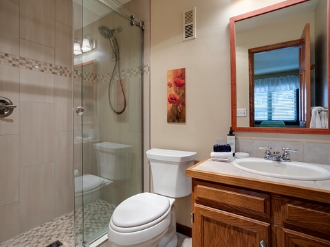 Your private bathroom features a spacious walk-in shower, elegant tile work, and warm wood vanity—fresh towels and everything you need for a relaxing stay await you.