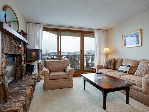 Cozy up by your stone fireplace while taking in sweeping mountain views from this inviting living space designed for relaxation and alpine serenity.