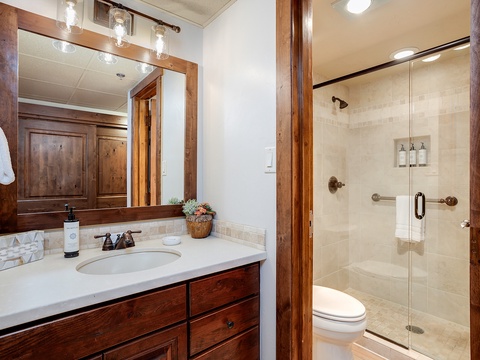 Your private bathroom features rich wood accents, a spacious vanity, and a beautifully tiled walk-in shower—perfect for refreshing after a day of adventure.