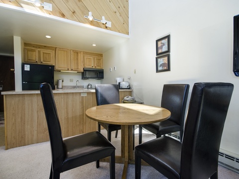 Gather around your private dining table for meals or game night, while enjoying the open-concept space flowing into your fully-equipped kitchen with modern black appliances and warm wood finishes.